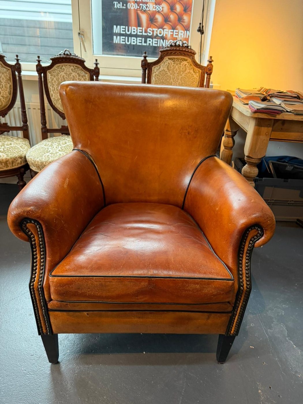 Cognac leren clubfauteuil voor herstoffering, dof en versleten